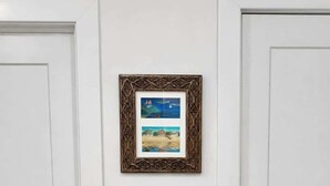 A white door with a keyhole and a lock, a framed picture above it, and a white horse sculpture on a wooden shelf below.