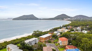 Eine Küstenstadt mit Strandhäusern, ein mehrstöckiges Gebäude im Zentrum und eine große Wasserfläche.