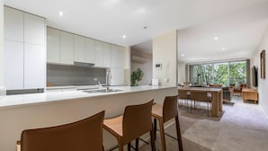 A modern kitchen with a central island, dining area with chairs, and a view of the outdoors. - Forrest Executive Apartment Parliament & Manuka Nearby (Forrest)