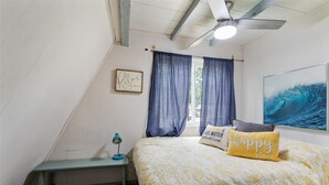 A bedroom with a bed, a desk, a ceiling fan, and a window with curtains.