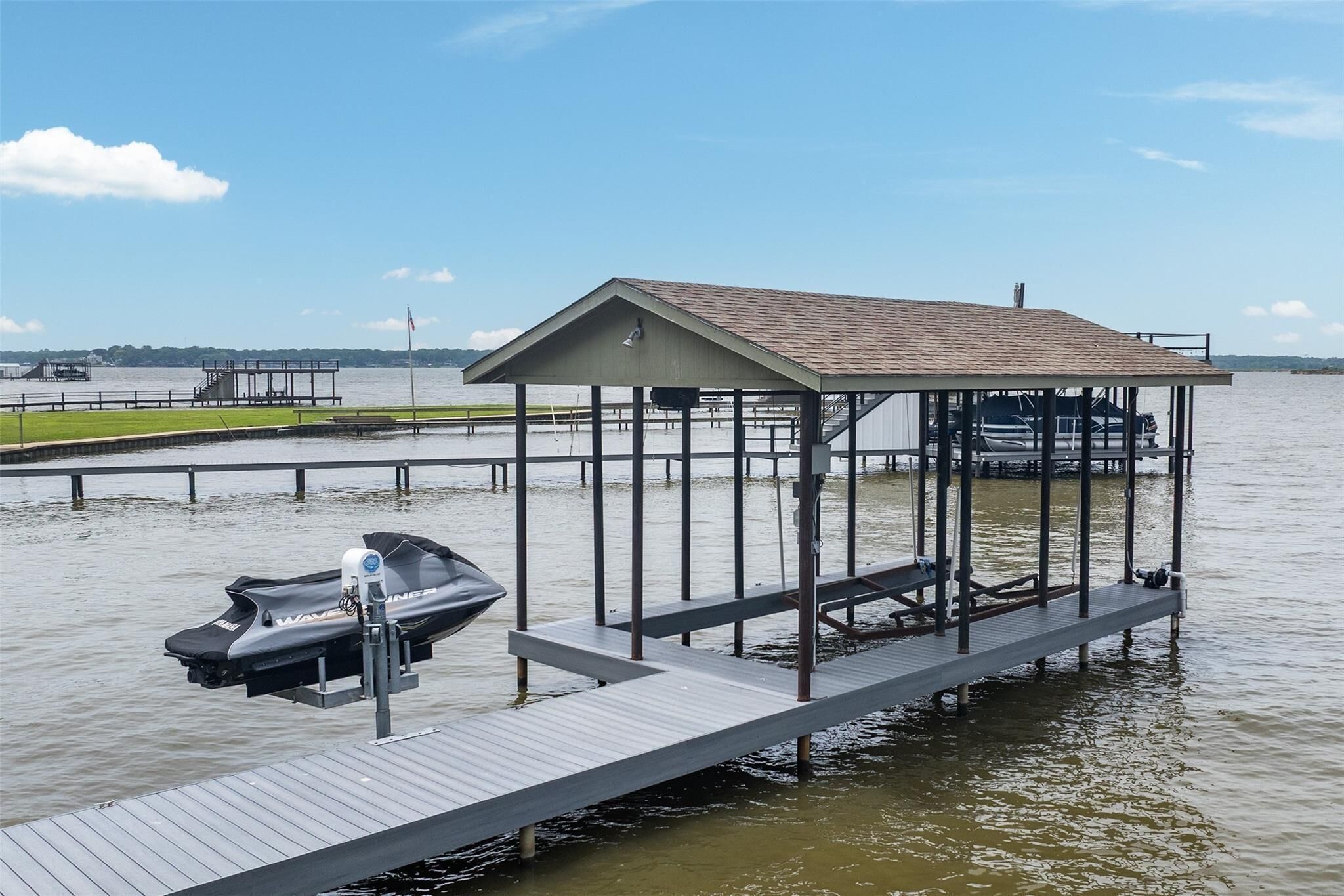 A dock with a covered seating area, a jet ski, and a boat.