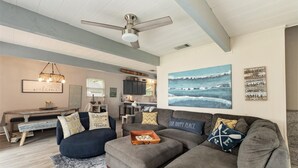 A cozy living room with a gray sectional sofa, a wooden coffee table, and a ceiling fan.