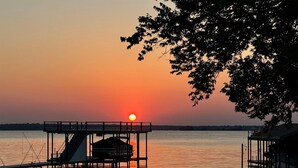 A dock extending into calm water with a sunset in the background.