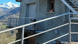 A multi-story building with a balcony, a staircase, and a view of snow-capped mountains.