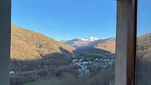 A window view of a valley with mountains, a river, and a small settlement.