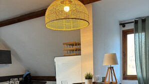 A kitchen with a wooden island, bar stools, a hanging light fixture, a lamp, and a window with curtains.