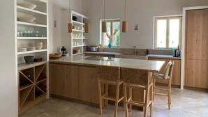 Una cocina moderna con vigas de madera, una isla central, taburetes de bar y estanterías empotradas.