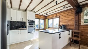 Una cocina con armarios blancos, una isla central y un techo de madera.