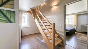 Interior moderno com escada de madeira que dá acesso a um quarto com janela.