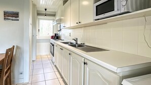 Une cuisine moderne avec des meubles blancs, un four à micro-ondes et une fenêtre qui laisse entrer la lumière naturelle.
