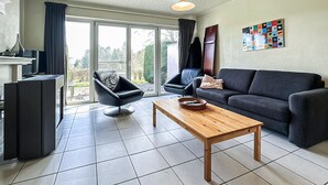 A living room with a sofa, armchair, coffee table, and a TV stand.