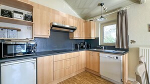 Eine kompakte Küche mit Holzausstattung, einer Mikrowelle, einer Kaffeemaschine und einem Geschirrspüler.