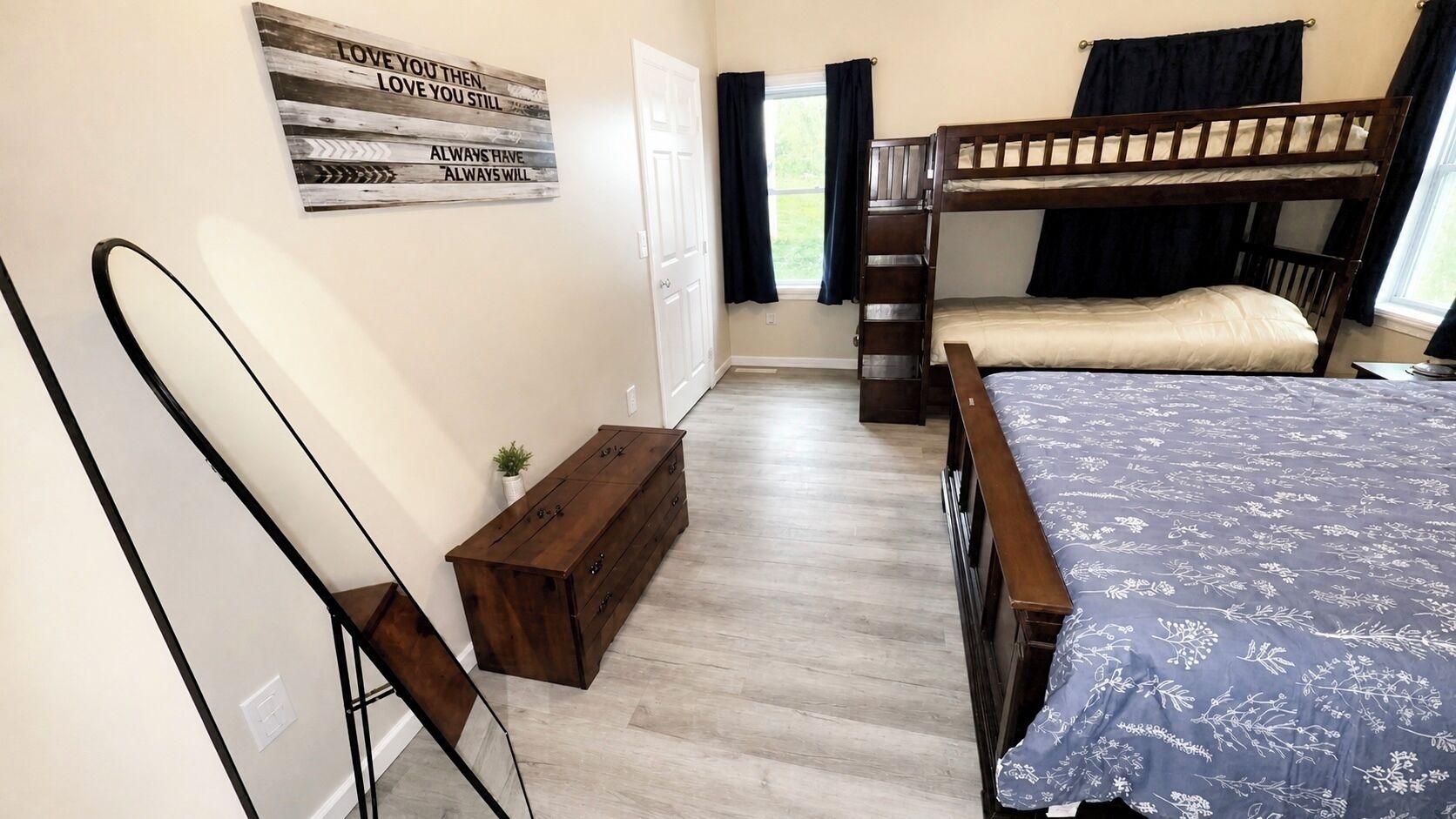 A bedroom with a bunk bed, a wooden dresser, a small bench, and a motivational poster on the wall.