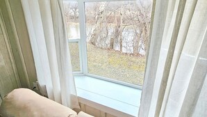 A room with a window, a beige sofa, and curtains.