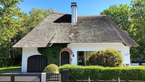 A small, single-story building with a thatched roof, a white exterior, and a black door. - Stunning home in Oostduinkerke with WiFi (Oostduinkerke)