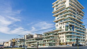 Ein mehrstöckiges, modernes Gebäude mit Balkonen und großen Fenstern unter blauem Himmel.