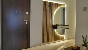 Ein moderner Flur mit Holztür, einem Wandspiegel und einem kleinen Tisch mit Pflanze.