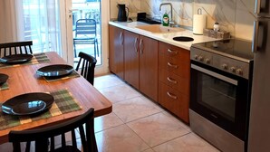 Eine moderne Küche mit Holzschränken, einem Edelstahlbackofen und einem Essbereich mit Tisch und Stühlen.