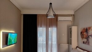 Ein Hotelzimmer mit einem Bett, einem wandmontierten Flachbildfernseher, einer Heizung, einem Fenster mit Vorhängen und einem Bild an der Wand.