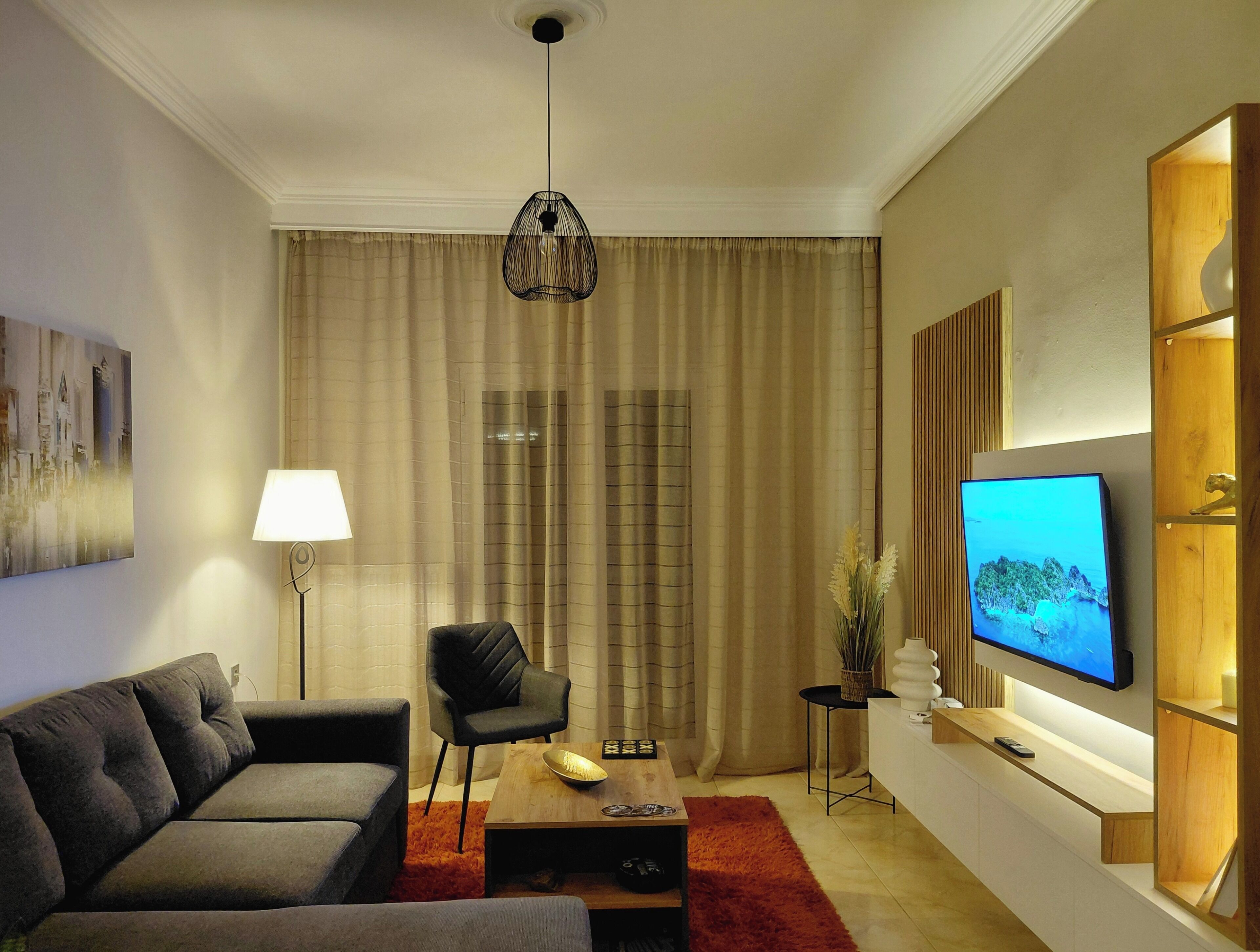 Ein modernes Wohnzimmer mit Sofa, Couchtisch, Fernseher und Lampe.