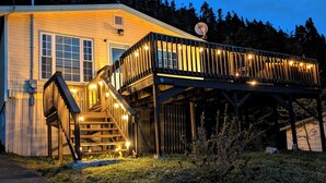 Un bâtiment à deux étages doté d’une terrasse en bois et d’un escalier menant à l’entrée.