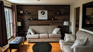 A living room with a sofa, a coffee table, and a wooden floor. - Cozy cottage located just over an hour to St. John's, NL! Pets welcome! (Placentia)