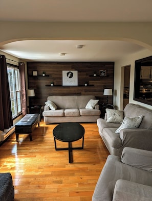Una sala de estar con un sofá, una mesa de centro y piso de madera.