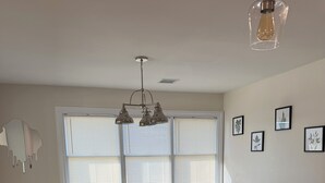 Una cocina con encimera de mármol, una zona de comedor con mesa y sillas, y una lámpara en el techo.