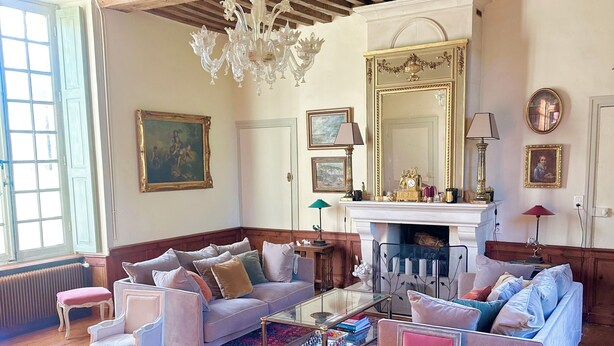 A room with wooden beams, a chandelier, a fireplace, and various pieces of furniture including sofas and chairs. - Charming 17th-Century French Manor (Le Breuil-en-Bessin)