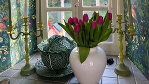 A room with a window, floral wallpaper, a vase with tulips, and candle holders. - Charming 17th-Century French Manor (Le Breuil-en-Bessin)
