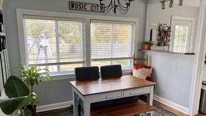 Uma sala de jantar com uma mesa de madeira, duas cadeiras, um banco, um vaso de plantas e um candelabro.
