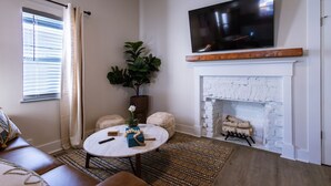 Un salon avec une cheminée, un téléviseur à écran plat, une table basse ronde et un canapé.