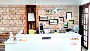 A reception desk with a clock, framed pictures, and a sign indicating no cash accepted. - Hostel Aldeia Inn (Fortaleza)