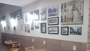 A dining area with a long wooden table and chairs, surrounded by walls adorned with framed pictures. - Hostel Aldeia Inn (Fortaleza)