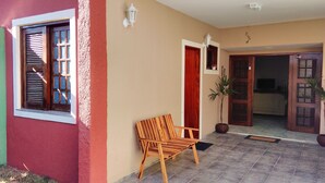 A wooden bench outside a building with a red wall and a door. - Hostel Aldeia Inn (Fortaleza)