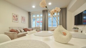 Una sala de estar moderna con un sofá, una mesa de centro, un florero con flores y un televisor de pantalla plana montado en la pared.