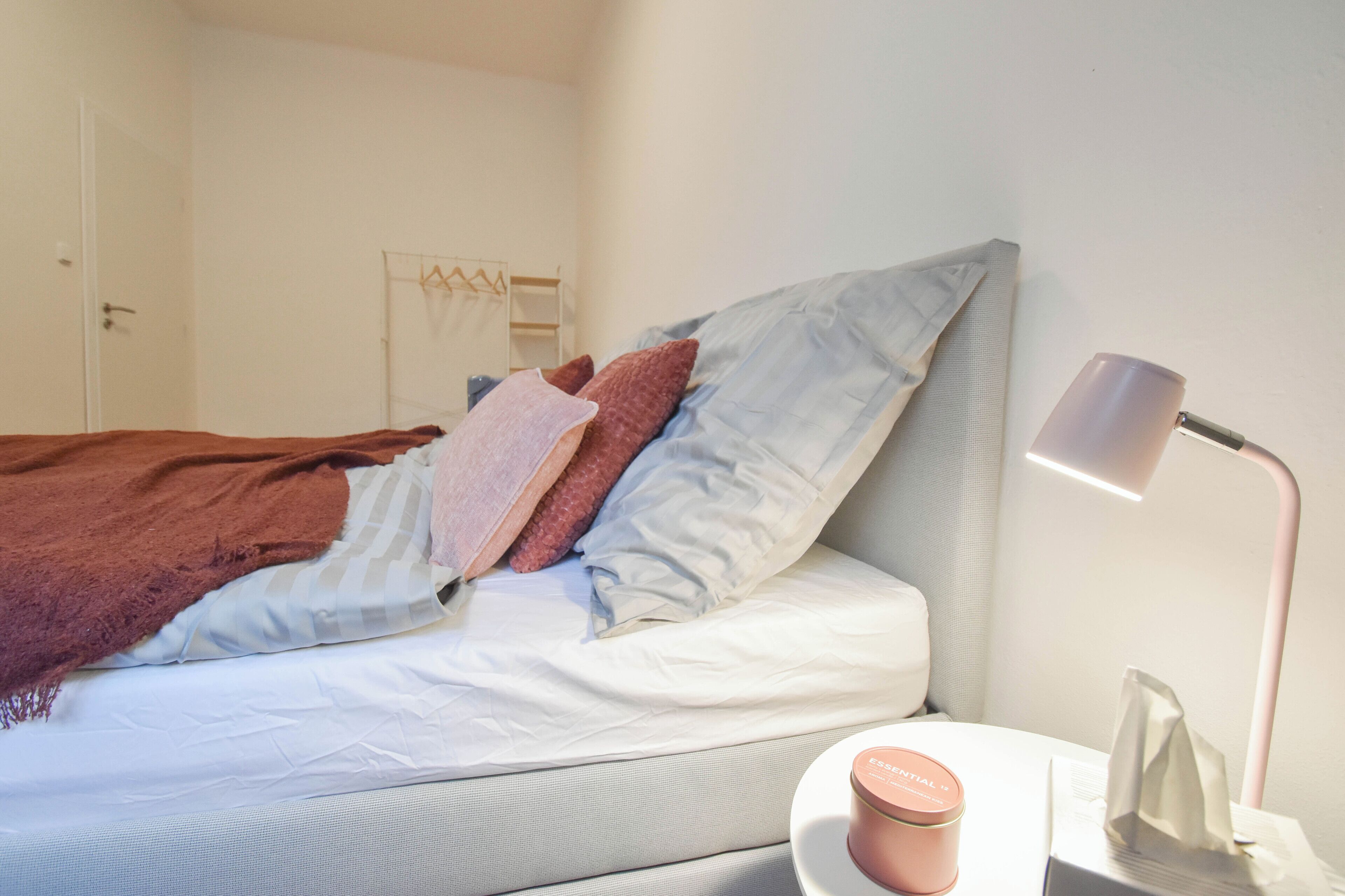 A neatly made bed with pillows, a bedside lamp, and a tissue box on a bedside table.