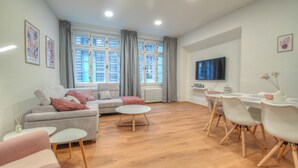 Una sala de estar moderna con sofá, mesa de centro, mesa de comedor, sillas y televisor.