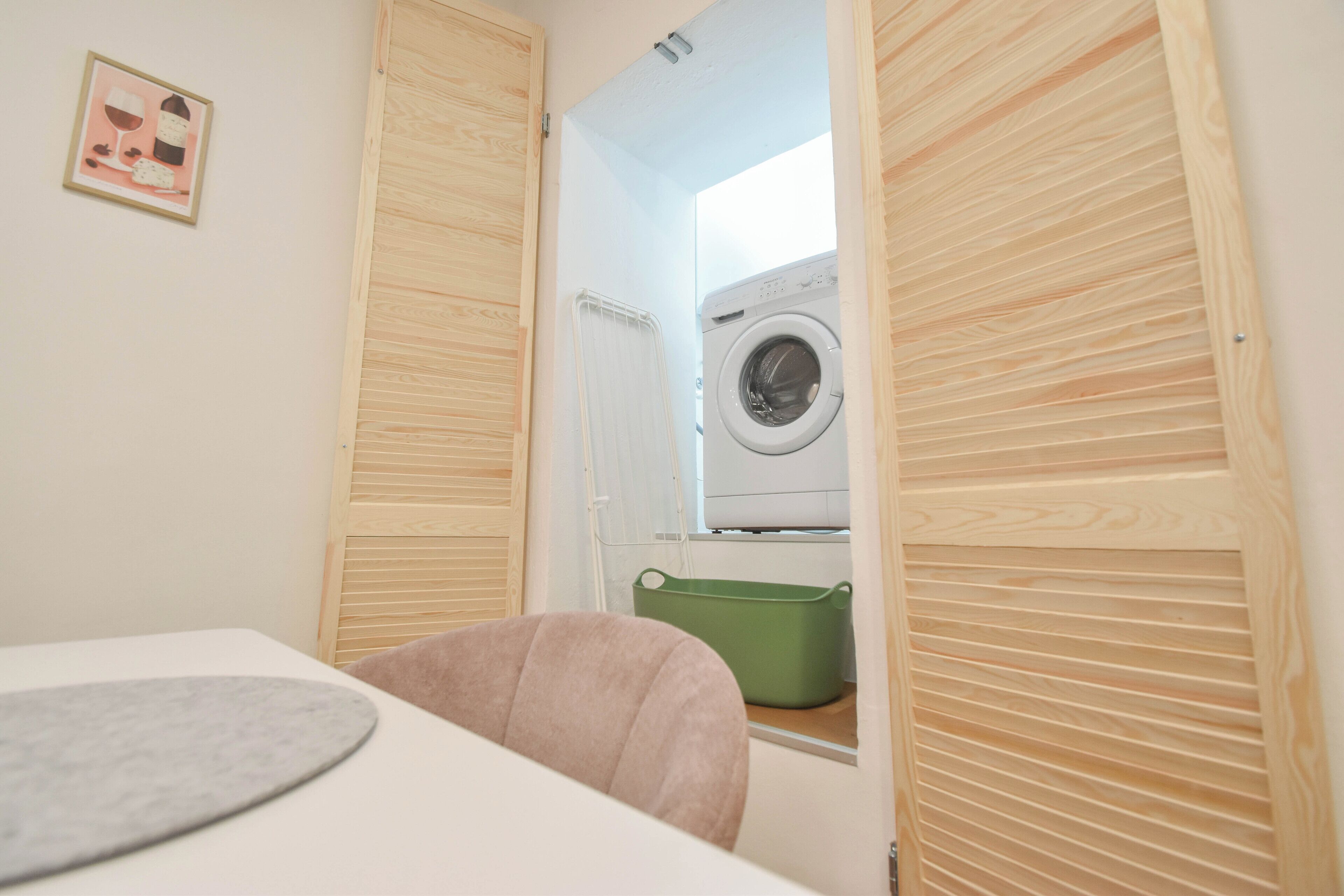 Een wasserette met een wasmachine, een droogrek en een groene mand.