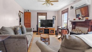A living room with a sofa, armchairs, a television, and a ceiling fan. - Delightful 3-bedroom house in charming Greenwich perfect for relaxing (Greenwich)