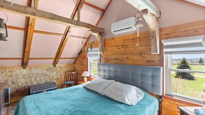 A bedroom with a bed, wooden walls, a window, and an air conditioning unit. - Delightful 3-bedroom house in charming Greenwich perfect for relaxing (Greenwich)
