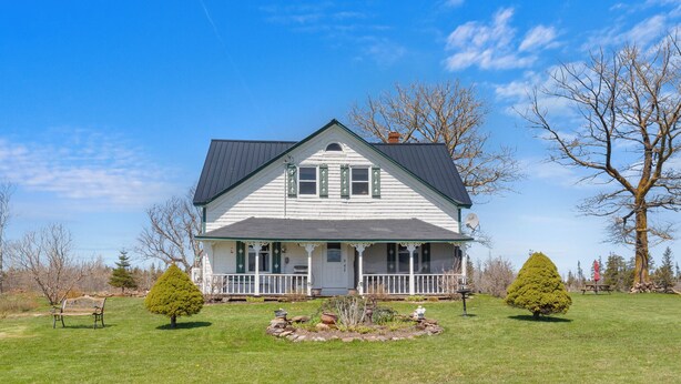 A white house with a dark roof, a front porch, and a well-maintained lawn with two small trees. - Delightful 3-bedroom house in charming Greenwich perfect for relaxing (Greenwich)