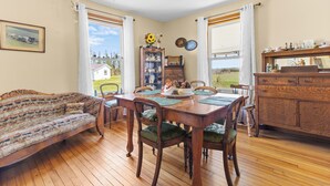 A dining room with a wooden table, chairs, a sofa, and a cabinet. - Delightful 3-bedroom house in charming Greenwich perfect for relaxing (Greenwich)