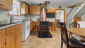 A kitchen with wooden cabinets, a stove, a sink, and a dining area with a table and chairs. - Delightful 3-bedroom house in charming Greenwich perfect for relaxing (Greenwich)