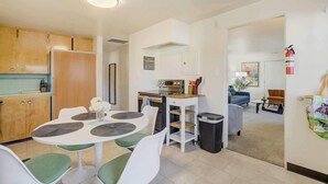 Una cocina moderna con comedor, una pequeña mesa con sillas y una sala de estar con sofá y mesa de centro.