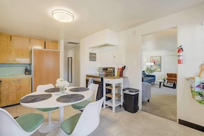 Una cocina moderna con comedor, una pequeña mesa con sillas y una sala de estar con sofá y mesa de centro.