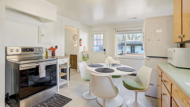 Una cocina moderna con horno empotrado, una mesa de comedor con sillas y un refrigerador.