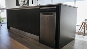A modern kitchen with a built-in dishwasher, dark cabinetry, and a large window providing natural light.
