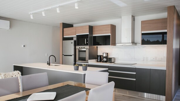 A modern kitchen with built-in appliances, a dining area with a table and chairs, and a view of the outdoors.
