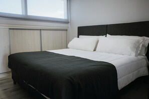 Un dormitorio con cama, ventana y armario.